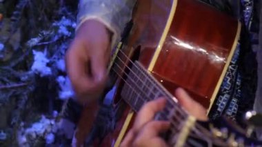 Kot ceketli bir gitarist enerjik bir şekilde akustik gitarla plectrum çalar.