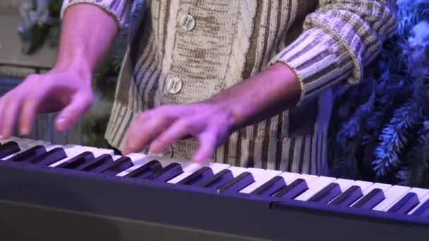 Homem com uma camisola de malha toca as teclas de piano — Vídeo de Stock