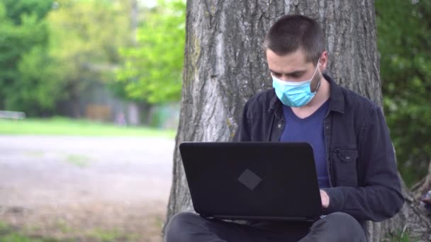 Joven Con Barba Una Máscara Médica Está Sentado Debajo Árbol — Vídeo de stock