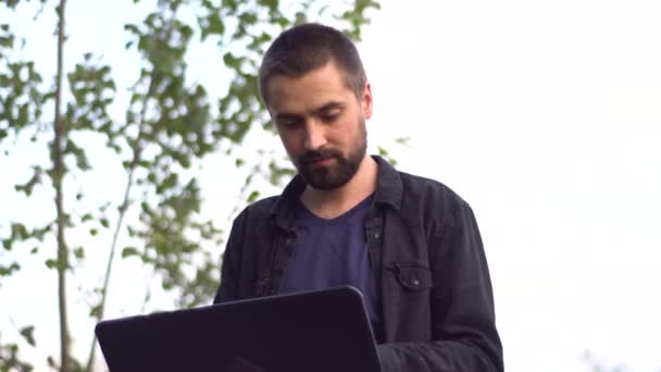 Joven Caucásico Serio Con Barba Está Sentado Parque Escribiendo Portátil — Vídeos de Stock