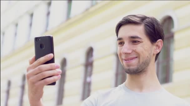 Joven Caucásico Sostiene Teléfono Mano Comunica Por Videollamada Bloguero Sonríe — Vídeos de Stock