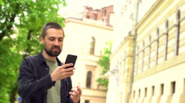 Sakallı beyaz blogcu takipçileriyle video üzerinden iletişim kurarken eğleniyor. Genç adam şehirde dolaşırken internette arkadaşlarıyla konuşuyor..