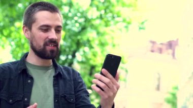 Sakallı, beyaz sakallı blogcu takipçileriyle videoda iletişim kurarken eğleniyor. Genç adam şehirde dolaşırken internette arkadaşlarıyla konuşuyor..