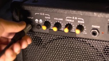 Gitar kablosunu bir amplifikatöre bağlıyorum. Yakın plan..