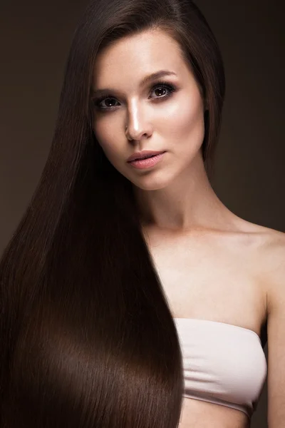 Piękna brunetka dziewczyna klasyczny makijaż i idealnie gładkie włosy. Piękna twarz. — Zdjęcie stockowe