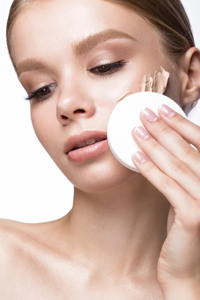 Hermosa joven con esponja para el maquillaje de aplicación y manicura francesa. Cara de belleza . — Foto de Stock