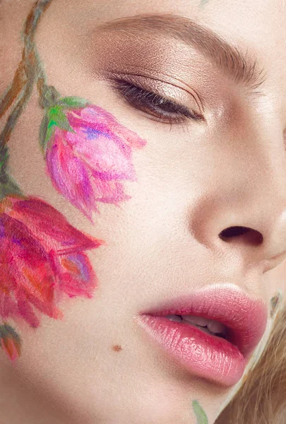 Hermosa chica rubia con rizos y un patrón floral en la cara. Flores de belleza . — Foto de Stock