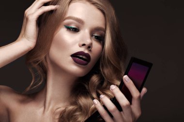 Güzel sarışın bir Hollywood şekilde ile bukleler, koyu dudaklar, elinde ayna. Güzellik ve saç.