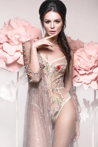 Mooi meisje met klassieke make-up en kapsel in delicate ondergoed met grote bloemen op achtergrond. schoonheid gezicht. — Stockfoto