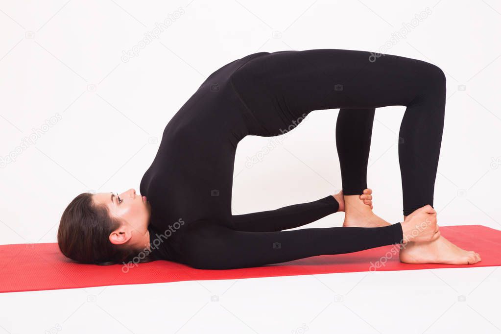 Beautiful athletic girl in black suit doing yoga. Ardha chakrasana - half bridge. Isolated on white background.