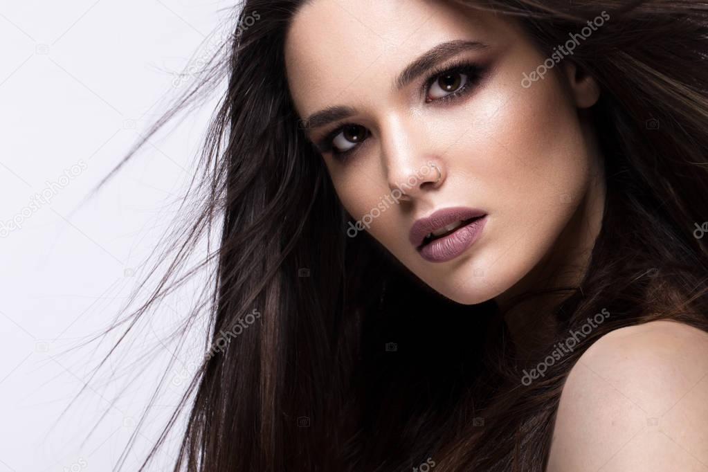 Beautiful brunette girl in move with a perfectly smooth hair, and classic make-up. Beauty face.