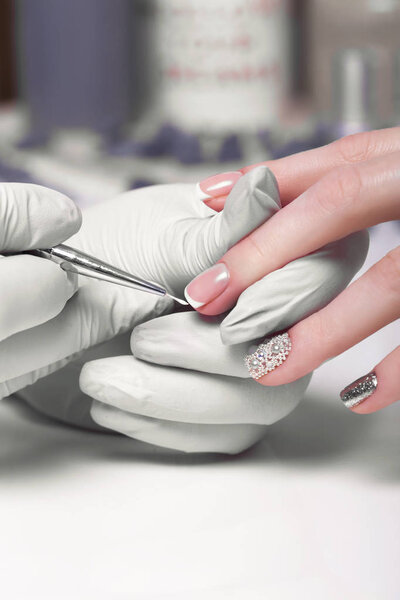 Closeup finger nail care by manicure specialist in beauty salon.