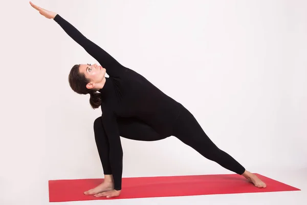 Mooi atletische meisje in zwart pak doen yoga asana's. Geïsoleerd op witte achtergrond. — Stockfoto