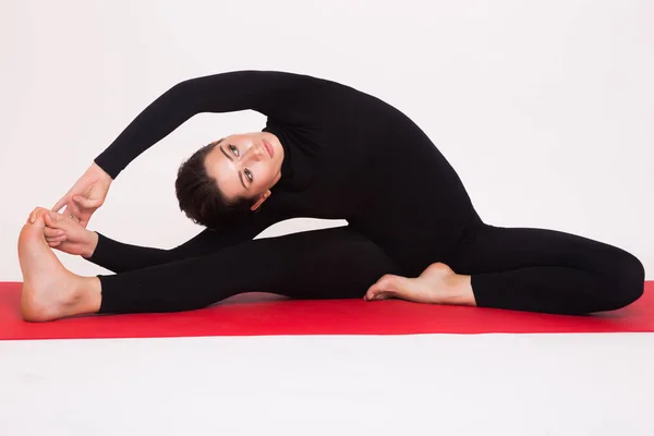 Menina atlética bonita em terno preto fazendo asanas de ioga. Isolado sobre fundo branco . — Fotografia de Stock