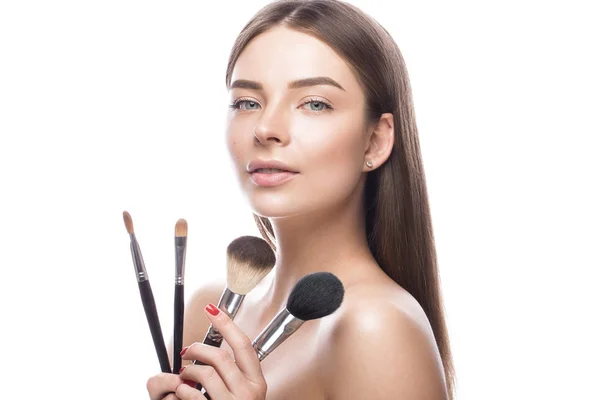 Hermosa joven con un maquillaje natural ligero, cepillos para cosméticos y piel perfecta. Cara de belleza . — Foto de Stock