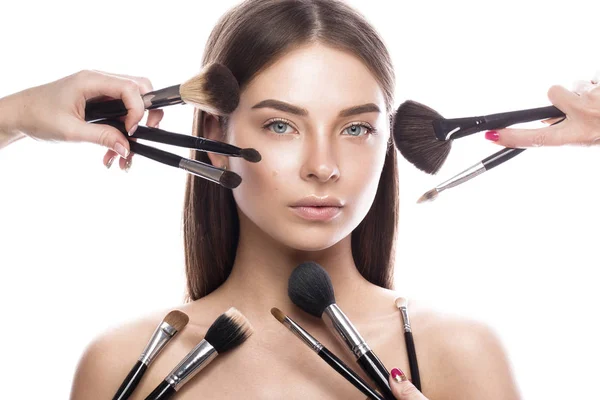 Mooi jong meisje met een lichte natuurlijke make-up, borstels voor cosmetica en perfecte huid. Schoonheid gezicht. — Stockfoto