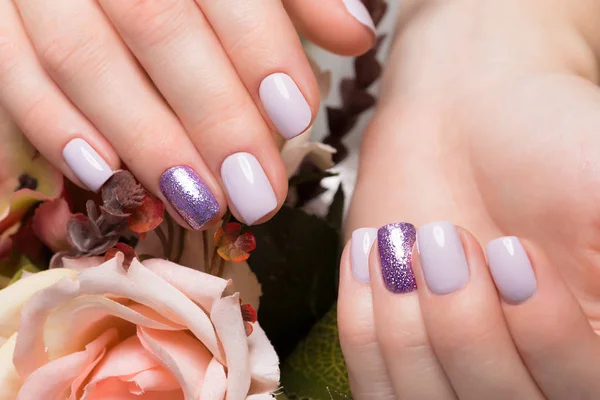 Purple neat manicure on female hands on flowers background. Nail design — Stock Photo, Image