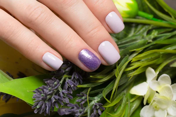 Manicure ordinata viola su mani femminili su sfondo di fiori. Progettazione unghie — Foto Stock