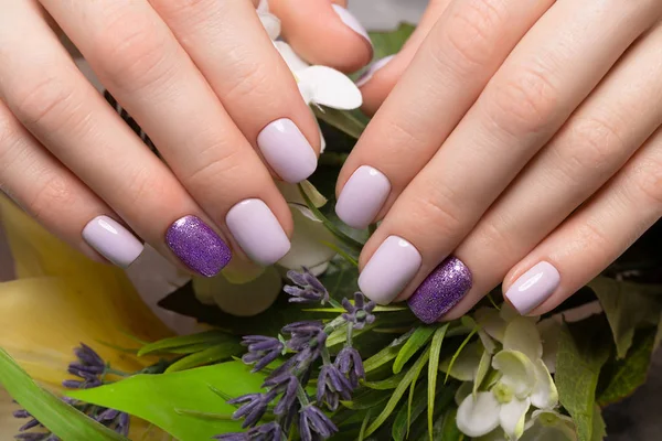 Fioletowy schludny manicure na kobieta ręce na tle kwiatów. Nail design — Zdjęcie stockowe