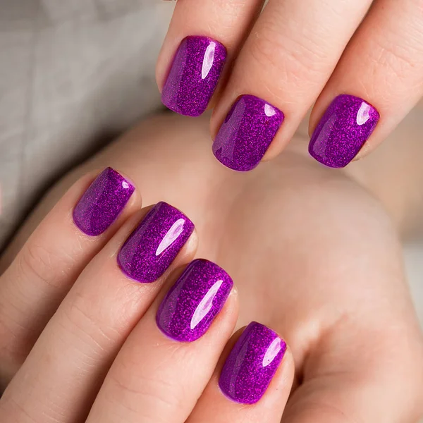 Manucure violette festive lumineuse sur les mains féminines. Conception des ongles — Photo