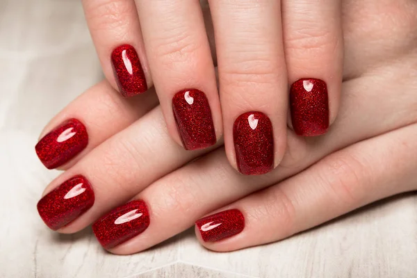 Manicura vermelha festiva brilhante em mãos femininas. Desenho de unhas — Fotografia de Stock