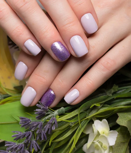 Manicure puro roxo em mãos femininas em fundo de flores. Desenho do prego — Fotografia de Stock