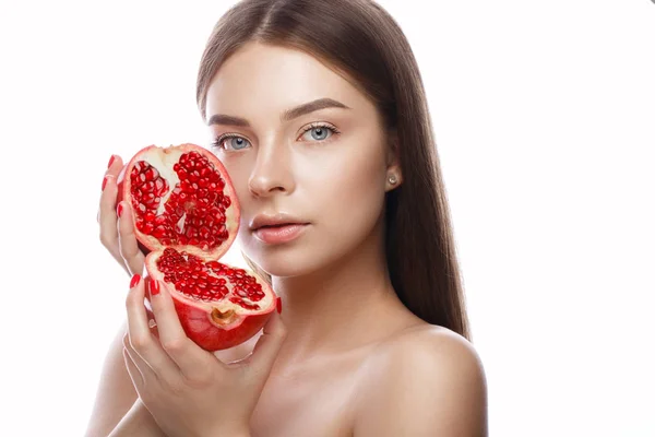 Vacker ung flicka med ljus naturlig make-up och perfekt hud med granatäpple i hennes hand. Vackert ansikte. — Stockfoto