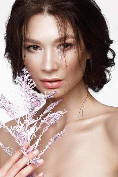 Mulher bonita com uma leve maquiagem natural e pele perfeita com flores na mão. Cara de beleza . — Fotografia de Stock