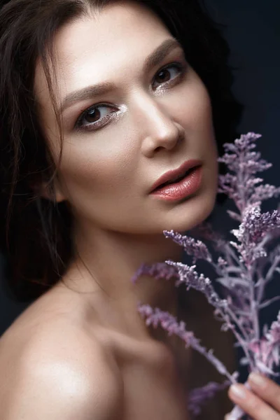 Mulher bonita com uma leve maquiagem natural e pele perfeita com flores na mão. Cara de beleza . — Fotografia de Stock