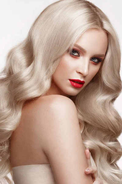 Beautiful blonde in a Hollywood manner with curls, natural makeup and red lips. Beauty face and hair.