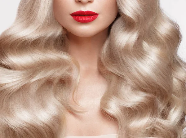 Beautiful blonde in a Hollywood manner with curls, natural makeup and red lips. Beauty face and hair.