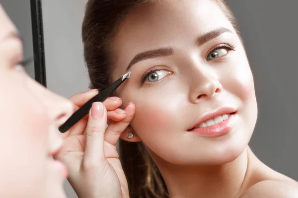 Vacker flicka gör sig själv en make-up i spegeln. Vackert ansikte. — Stockfoto