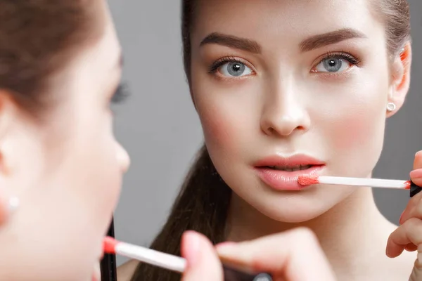 Mooi meisje maakt zelf een make-up in de spiegel. Schoonheid gezicht. — Stockfoto