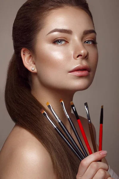 Vacker ung flicka med naturlig naken make-up med kosmetiska verktyg i händerna. Skönhetsansikte. — Stockfoto
