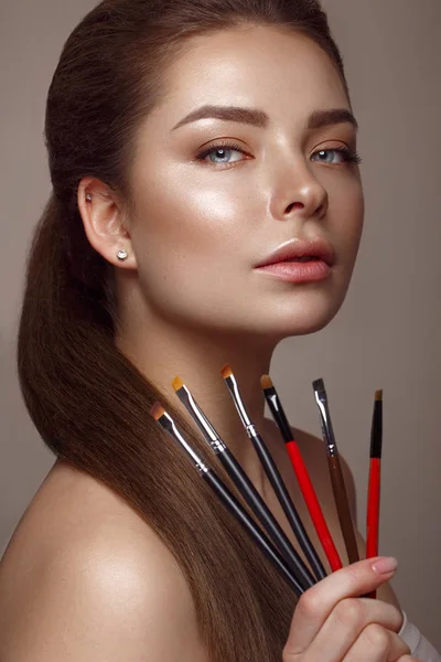 Beautiful young girl with natural nude make-up with cosmetic tools in hands. Beauty face. — Stock Photo, Image