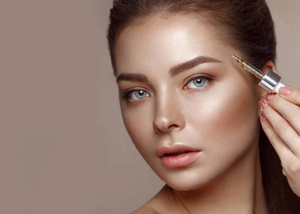 Mooi jong meisje met natuurlijke naakte make-up met cosmetische in handen. Schoonheidsgezicht. — Stockfoto