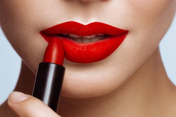 Schönes Mädchen mit roten Lippen und klassischem Make-up mit Lippenstift in der Hand. Schönheit Gesicht — Stockfoto