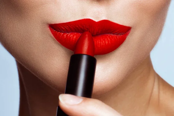 Schönes Mädchen mit roten Lippen und klassischem Make-up mit Lippenstift in der Hand. Schönheit Gesicht — Stockfoto
