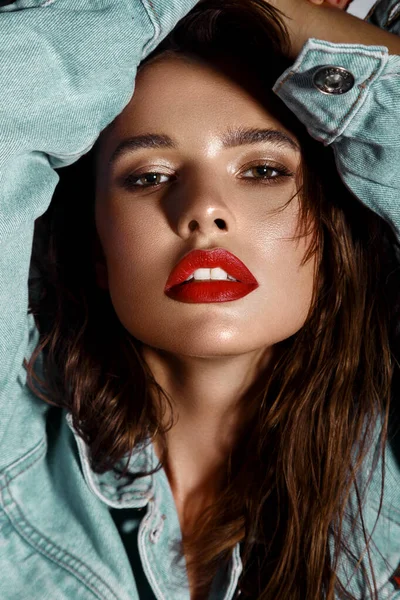 Menina sexy bonita com maquiagem brilhante, lábios vermelhos, cabelo molhado em uma jaqueta de ganga. Cara de beleza — Fotografia de Stock