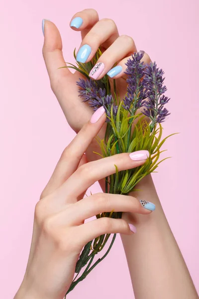 Manicure rosa e azul bonito com cristais na mão feminina com flores. Close-up . — Fotografia de Stock