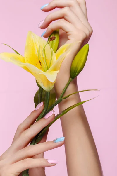 Piękny różowo-niebieski manicure z kryształkami na kobiecej dłoni z kwiatami. Zbliżenie. — Zdjęcie stockowe