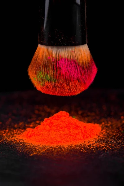 Pennello guancia con polvere cosmetica al neon colorato mucchio su sfondo nero — Foto Stock