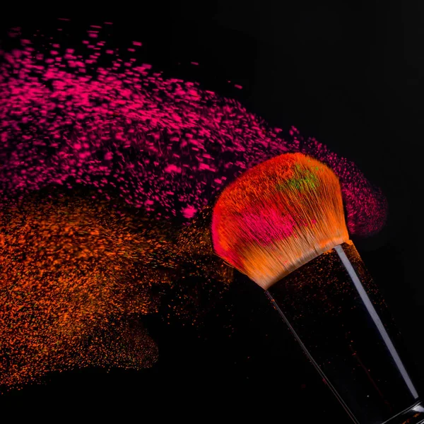 Pennello guancia con neon cosmetico in polvere spray colorato su sfondo nero — Foto Stock