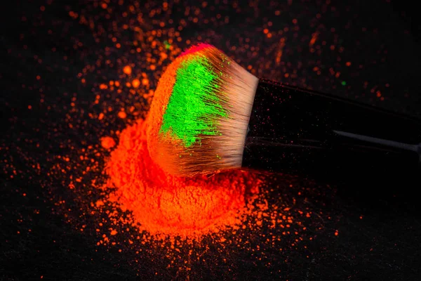 Pennello guancia con polvere cosmetica al neon colorato mucchio su sfondo nero — Foto Stock