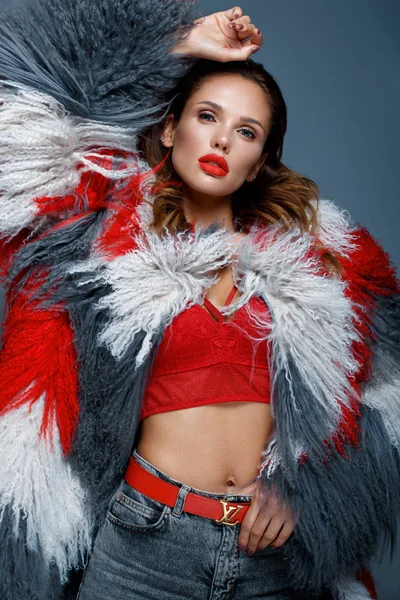 Hermosa mujer con maquillaje clásico de vacaciones, labios rojos, rizos en un abrigo de llama multicolor. Cara de belleza. —  Fotos de Stock