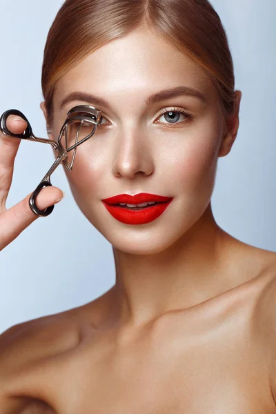 Schönes Mädchen mit roten Lippen und klassischem Make-up mit Lockenwickler in der Hand. Schönheit Gesicht. — Stockfoto