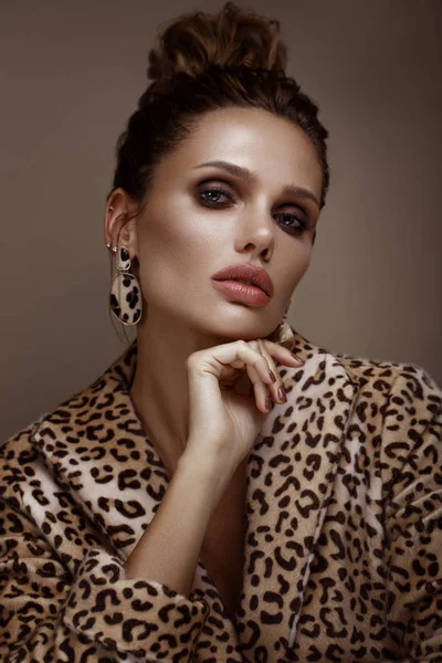 Bella donna sexy in un cappotto di leopardo e orecchini, con trucco classico fumoso e un'acconciatura alla moda. Bellezza viso . — Foto Stock