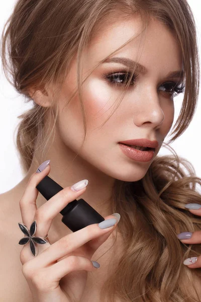 Pretty girl with easy hairstyle, classic makeup, nude lips and manicure design with jar of nail polish in her hands. Beauty face.