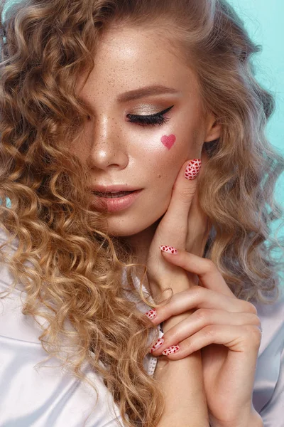 Chica bonita con rizos peinado, maquillaje clásico, pecas, labios desnudos y diseño de manicura con corazones. Cara de belleza. La imagen para el Día de San Valentín —  Fotos de Stock