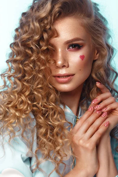 Chica bonita con rizos peinado, maquillaje clásico, pecas, labios desnudos y diseño de manicura con corazones. Cara de belleza. La imagen para el Día de San Valentín —  Fotos de Stock